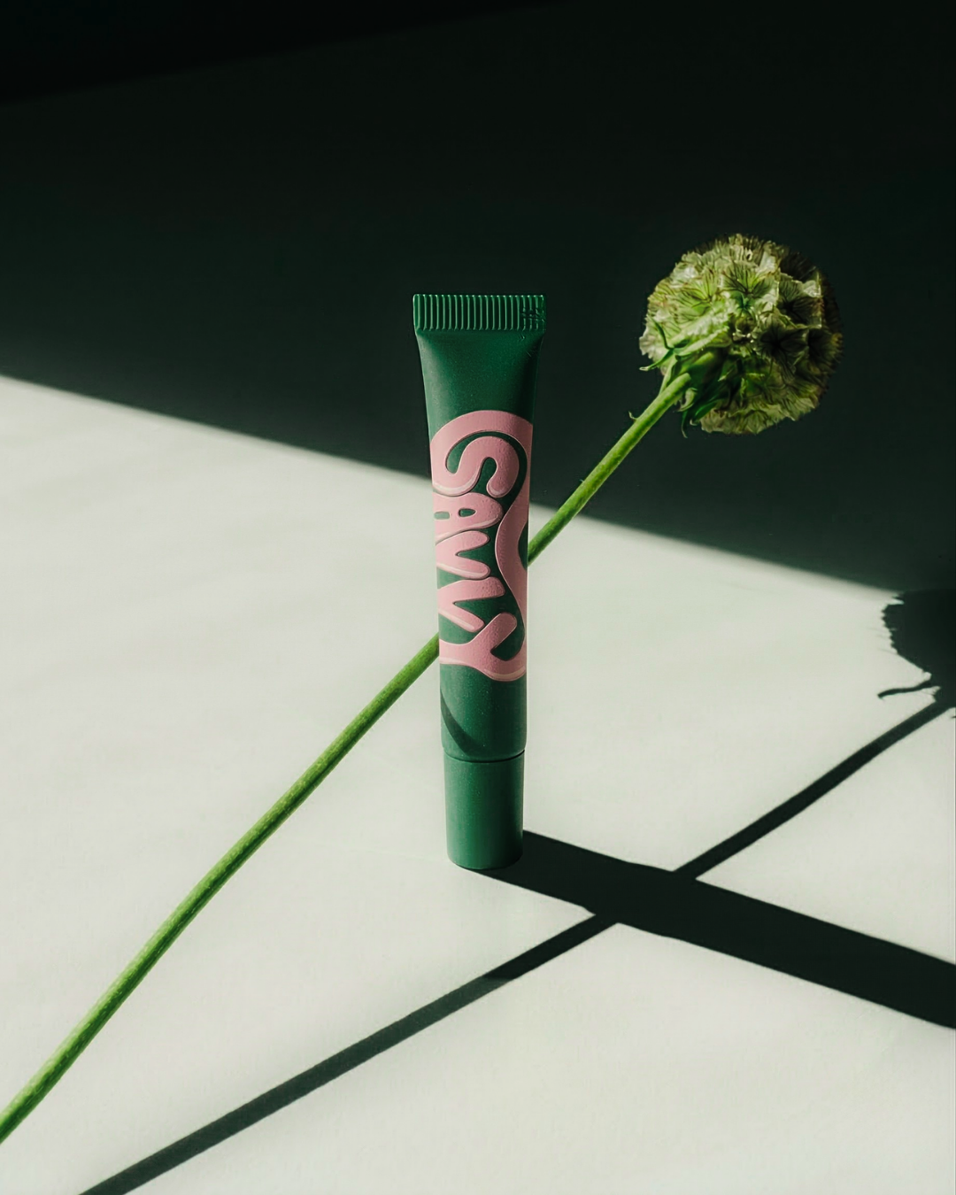 Savvy Body Glue tube with a green flower