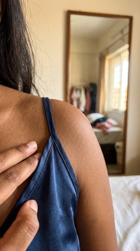 A customer pressing a satin strap flat against her shoulder.